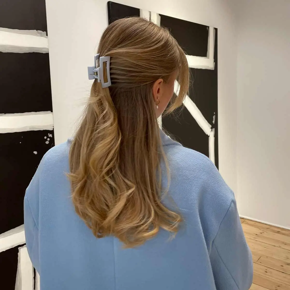 Mädchen mit halb hochgestecktem Haar und pastellblauer Haarspange – passende Jacke in einem Museum.